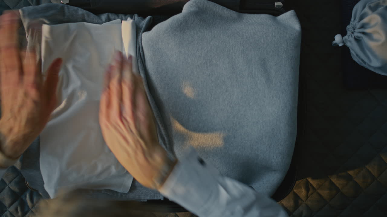 Mature Man Carefully Folding and Packing Clothes Into Suitcase on Neatly Made Hotel Bed (Stock Footage)