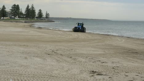tractor sweeps and cleans beachfront near the ocean