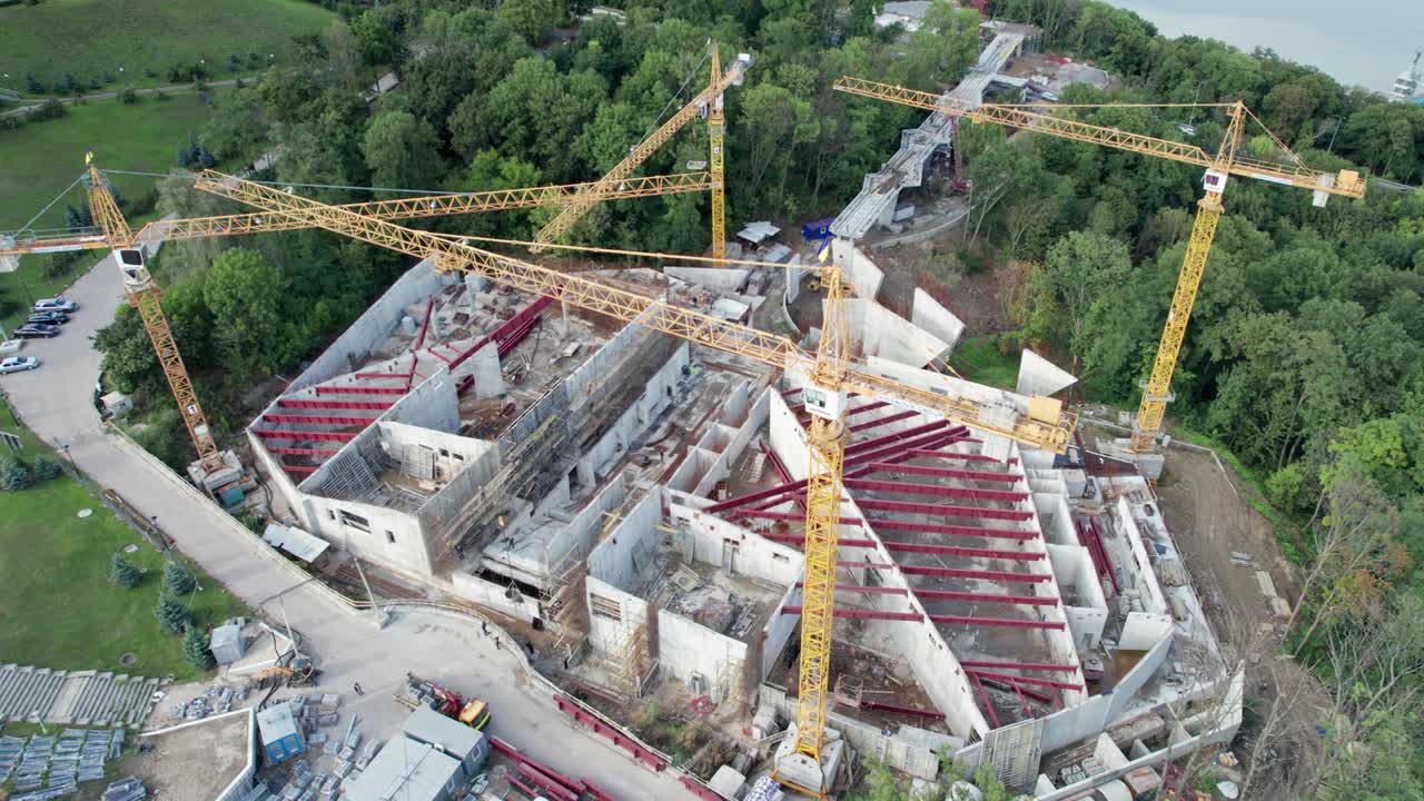 vista aérea construcción de un nuevo edificio con grúas de torre altas en área verde
