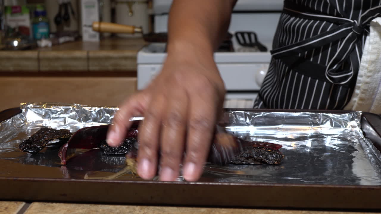 Woman takes dried red peppers out of plastic bag and spreads on tray with foil