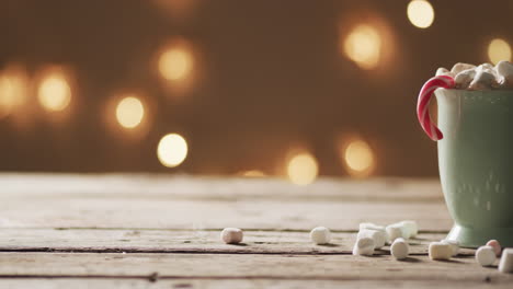 video of mug of chocolate, marshmallows, christmas decorations and copy space on wooden background