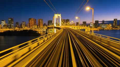 tokyo cityscape with rainbow bridge and train tracks at dusk