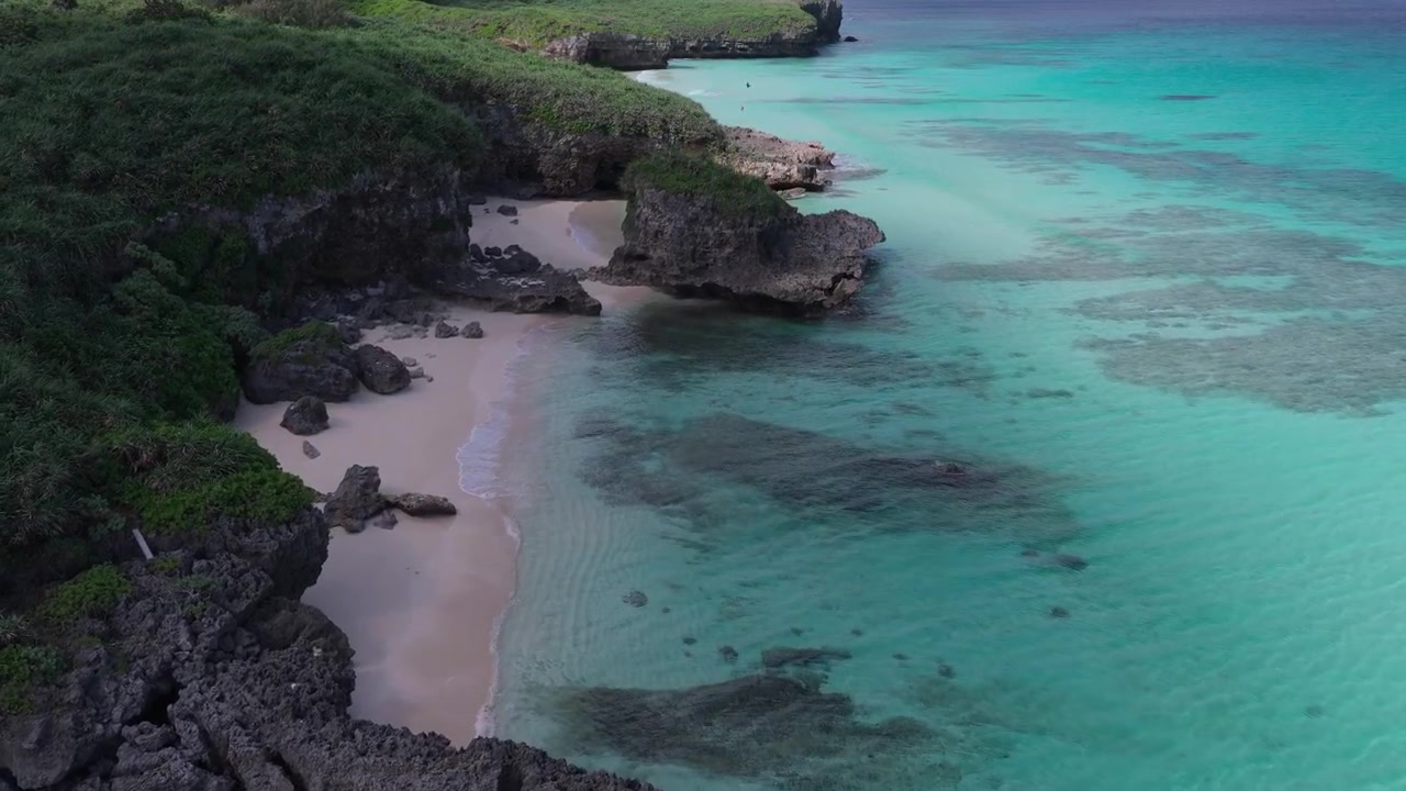 Riprese aeree orizzontali che avanzano lungo la costa rocciosa e le acque turchesi di Sunayama Beach e Nikawatori Beach, Miyakojima, Okinawa, Giappone.
