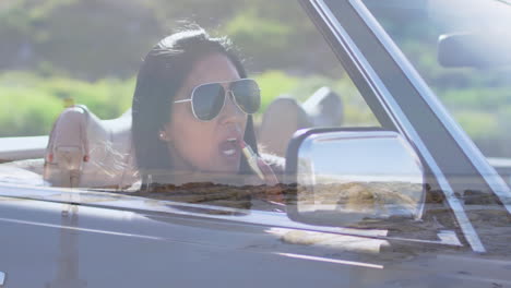 driving convertible with scenic landscape reflection, woman wearing sunglasses