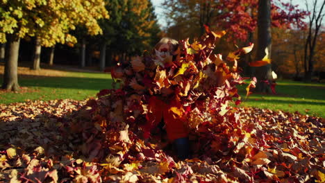 child having fun playing in autumn leaves