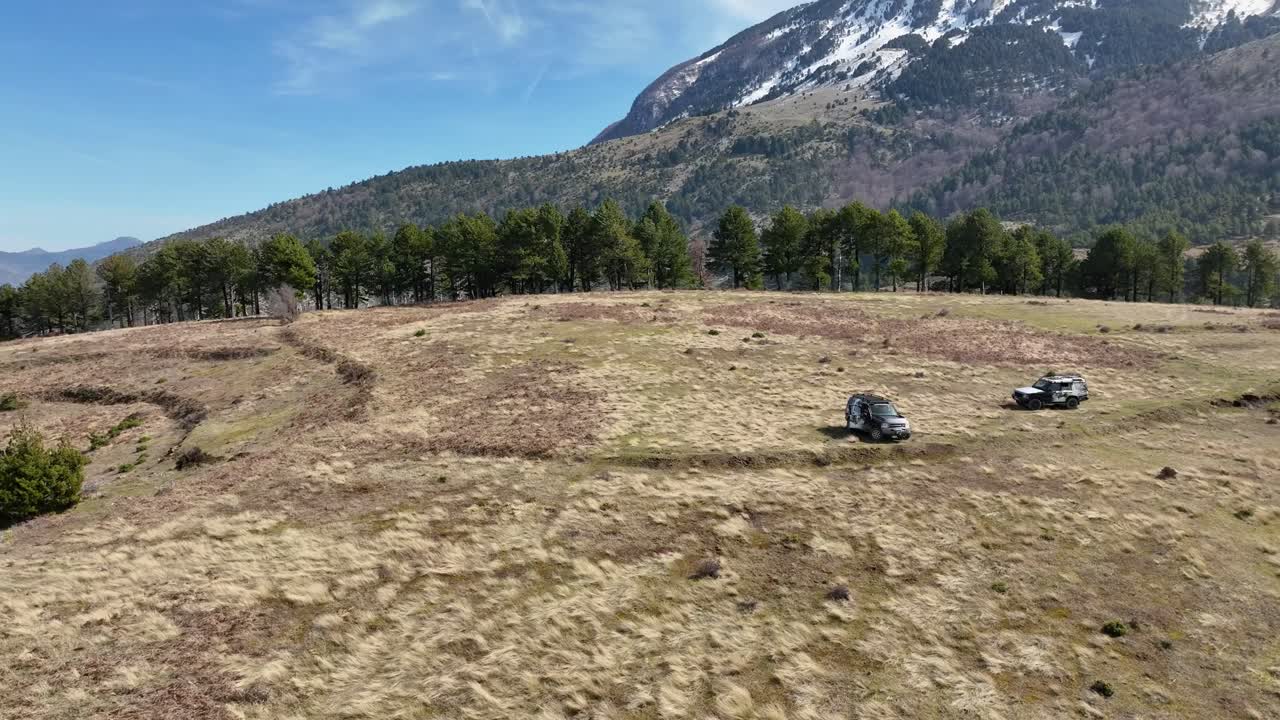 두 대의 오프 로드 자동차가 산의 경사에서 멈추고 산의 꼭대기가 배경입니다.