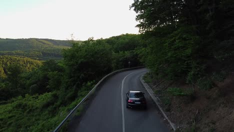 Vista-Aérea-De-Un-Coche-Que-Pasa-Por-Un-Camino-Rizado-En-Un-Bosque-Durante-El-Verano