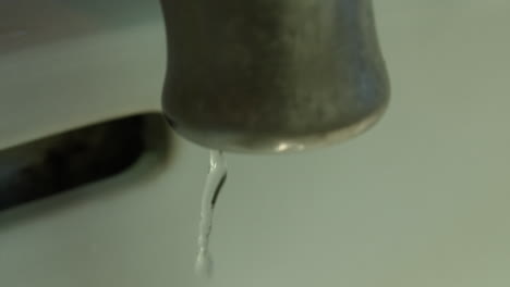 Slow-motion-medium-closeup-of-a-faucet-as-the-water-runs-and-then-slowly-shuts-off