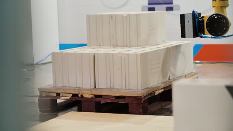 brazo robótico que maneja bloques de cerámica en una paleta