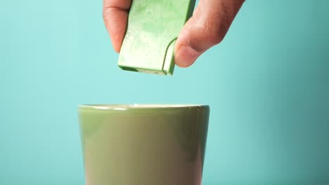 close-up of a hand pouring sugar into a green cup