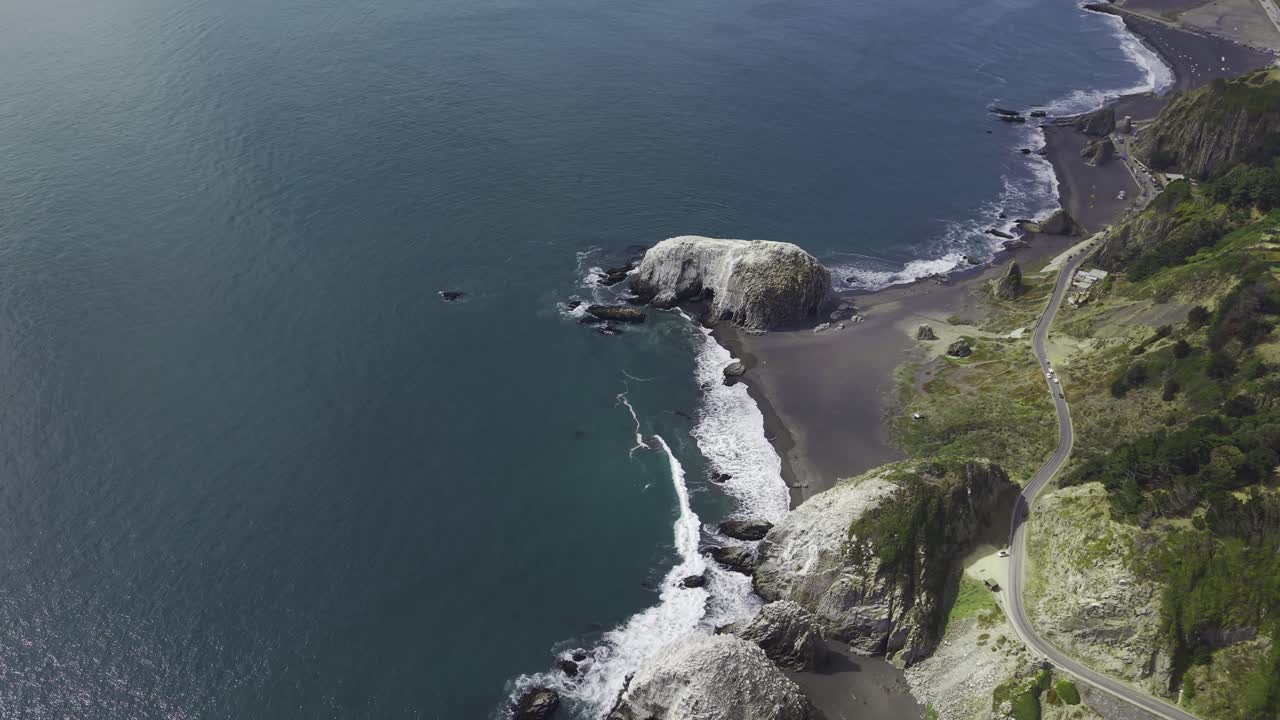 Sorvolando in alto la costa verso Piedra de la Iglesia, seguendo la strada sulla scogliera e la costa di sabbia nera vicino a Constitución Maule Cile, 4K