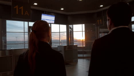 Hombre-Y-Mujer-Disfrutando-Del-Atardecer-A-Través-De-La-Ventana-Del-Aeropuerto