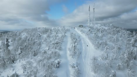 snowy mountaintop with skiers and radio tower