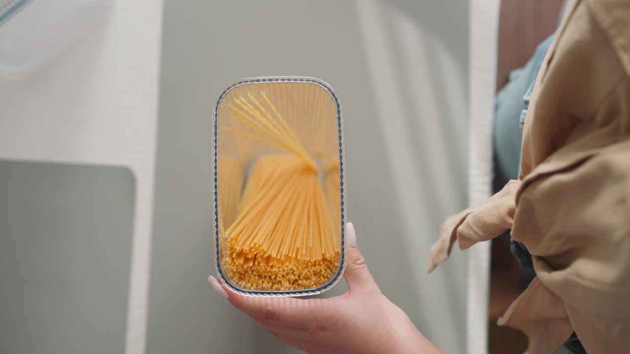 la mujer pone espagueti en un recipiente transparente y agita