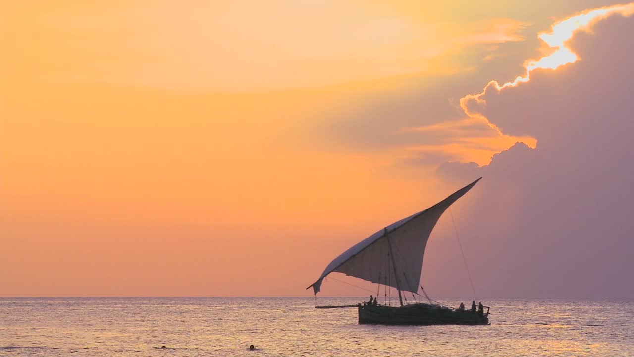 아름다운 일몰을 배경으로 잔지바르 해안을 따라 항해하는 도우 범선의 아름다운 샷