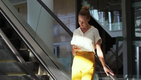 Young-businesswoman-on-an-escalator-in-a-modern-building