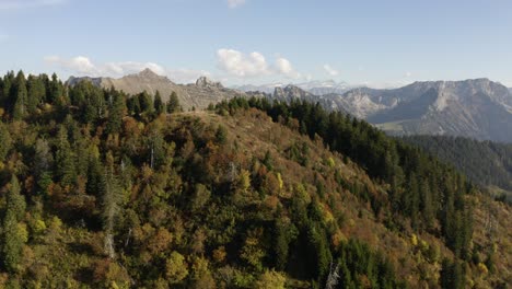 overflying high hill with hikers on top, revealing alpine landscape in the background