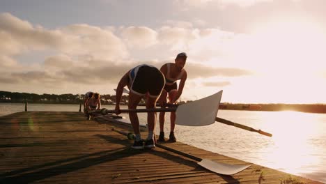 remador masculino sosteniendo remos en el muelle