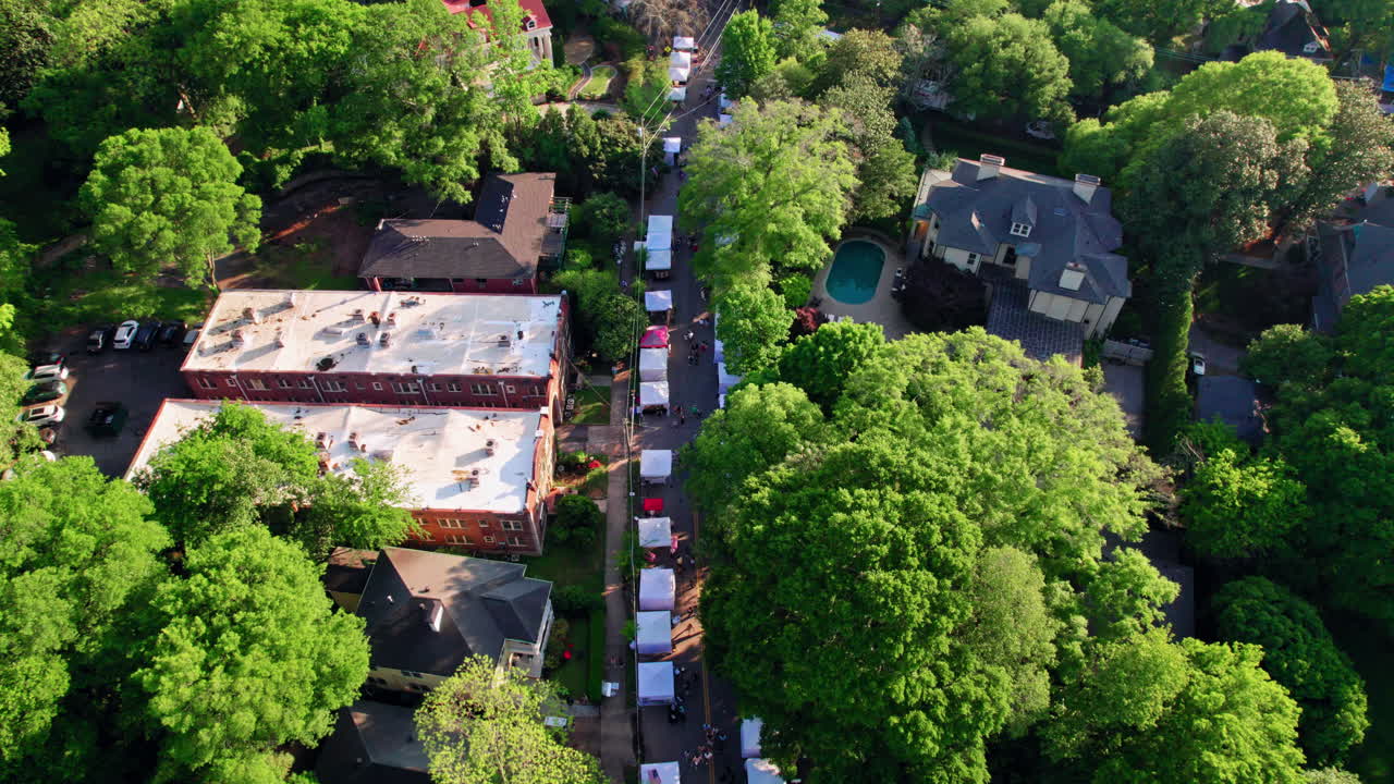 Una ripresa aerea ascendente sopra le tende dei venditori locali all'Inman Park Festival, un evento primaverile molto popolare in uno storico quartiere di Atlanta, Georgia, con una vivace chioma urbana e parchi e strade panoramiche