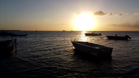 Vuelo-Aéreo-Cercano-Sobre-Los-Barcos-Durante-El-Reflejo-Del-Sol-En-El-Océano,-Silueta