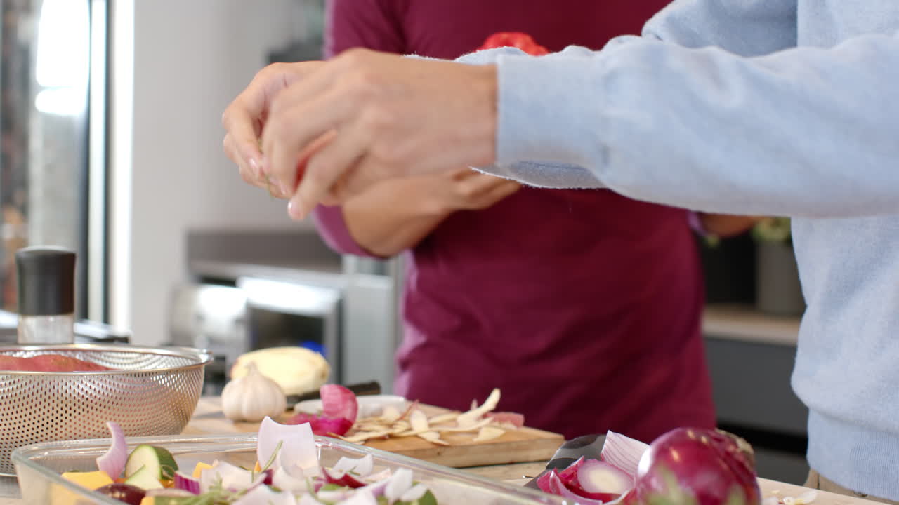 Chopping vegetables, man preparing meal in kitchen with partner assisting, at home
