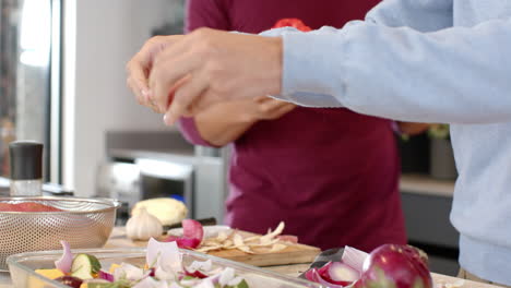 chopping vegetables, man preparing meal in kitchen with partner assisting, at home