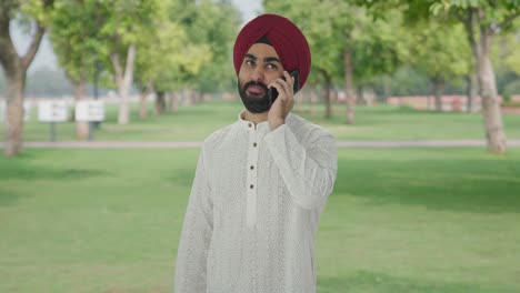 happy sikh indian man talking on phone in park