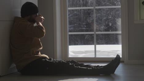 Man-Drinking-Coffee-Indoors-Watching-Snow-Landscape-Outdoors