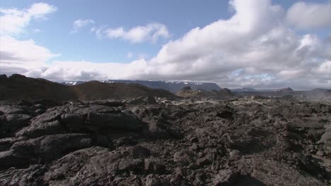 Lava-field-in-Iceland-long-shot-with-blue-sky-and-some-clouds,-steam-rising-from-the-ground