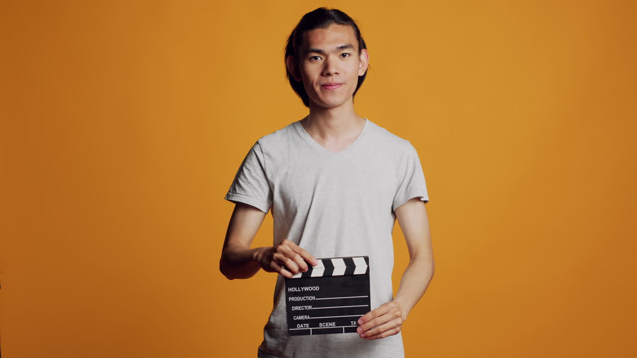 Casual modern man using film slate in studio