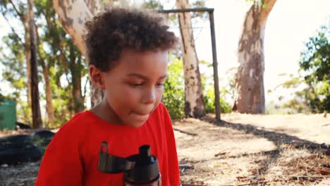 niño deshidratado bebiendo una botella de agua durante una carrera de obstáculos