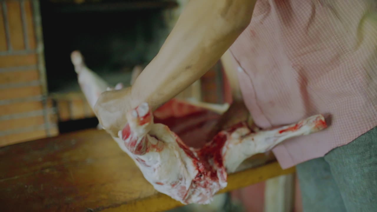A person is pulling apart the rib cage of a butchered animal on a cutting board