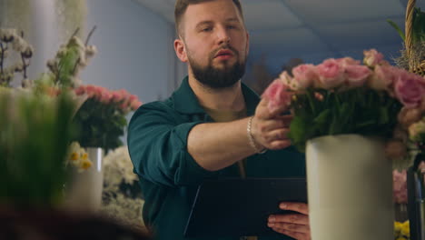 Florista-Masculino-Cuenta-Flores-En-Un-Jarrón-Y-Toma-El-Orden-Usando-Una-Tableta