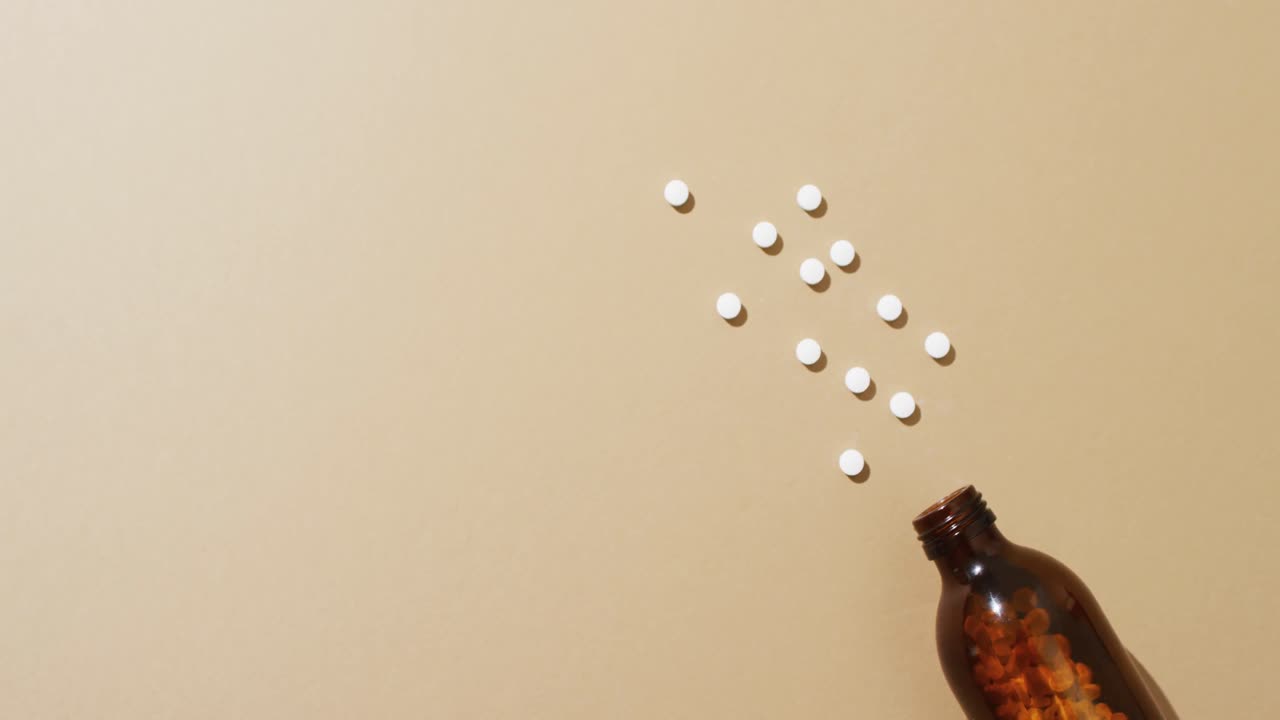 video de una botella marrón derramando píldoras blancas sobre un fondo marrón con espacio para copiar