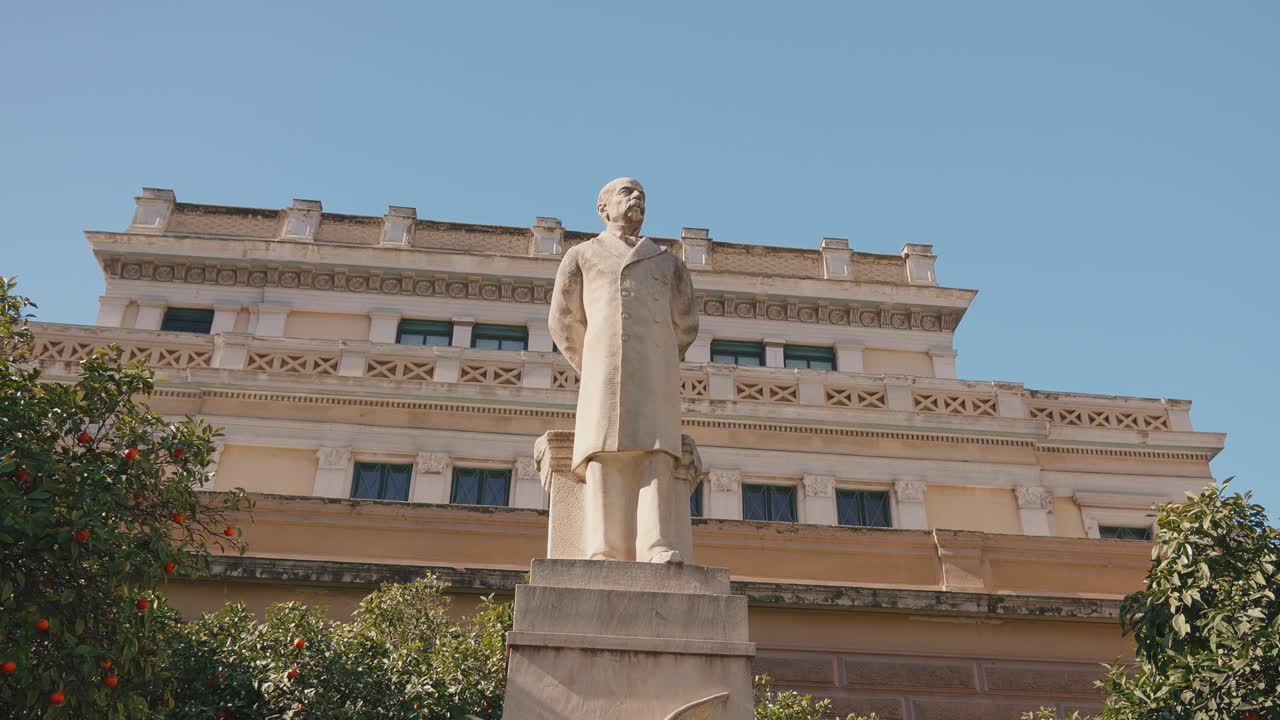 Statua di Charilaos Trikoupis con edificio storico, giornata di sole