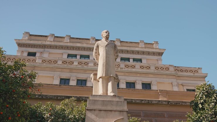 Statua di Charilaos Trikoupis con edificio storico, giornata di sole