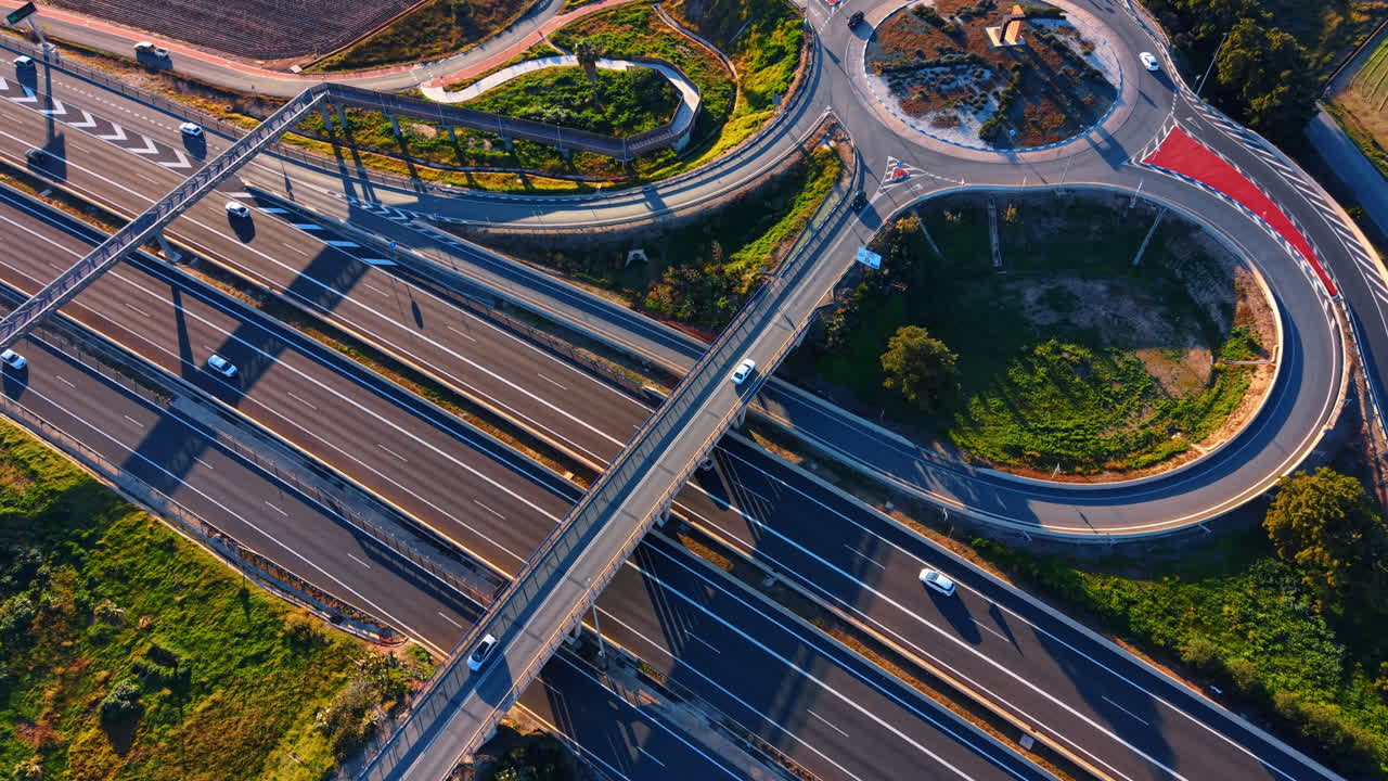 Highway interchange and traffic roundabout. High angle view of asphalt roads merging into a roundabout near agricultural fields at sunset