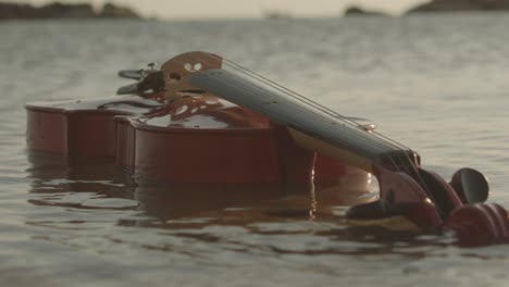 un violín clásico está flotando en el agua de mar