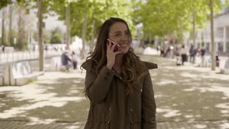 smiling young woman talking on phone in park.