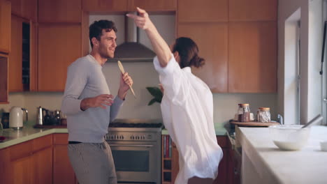 Singing,-happy-or-couple-in-home-kitchen-bonding