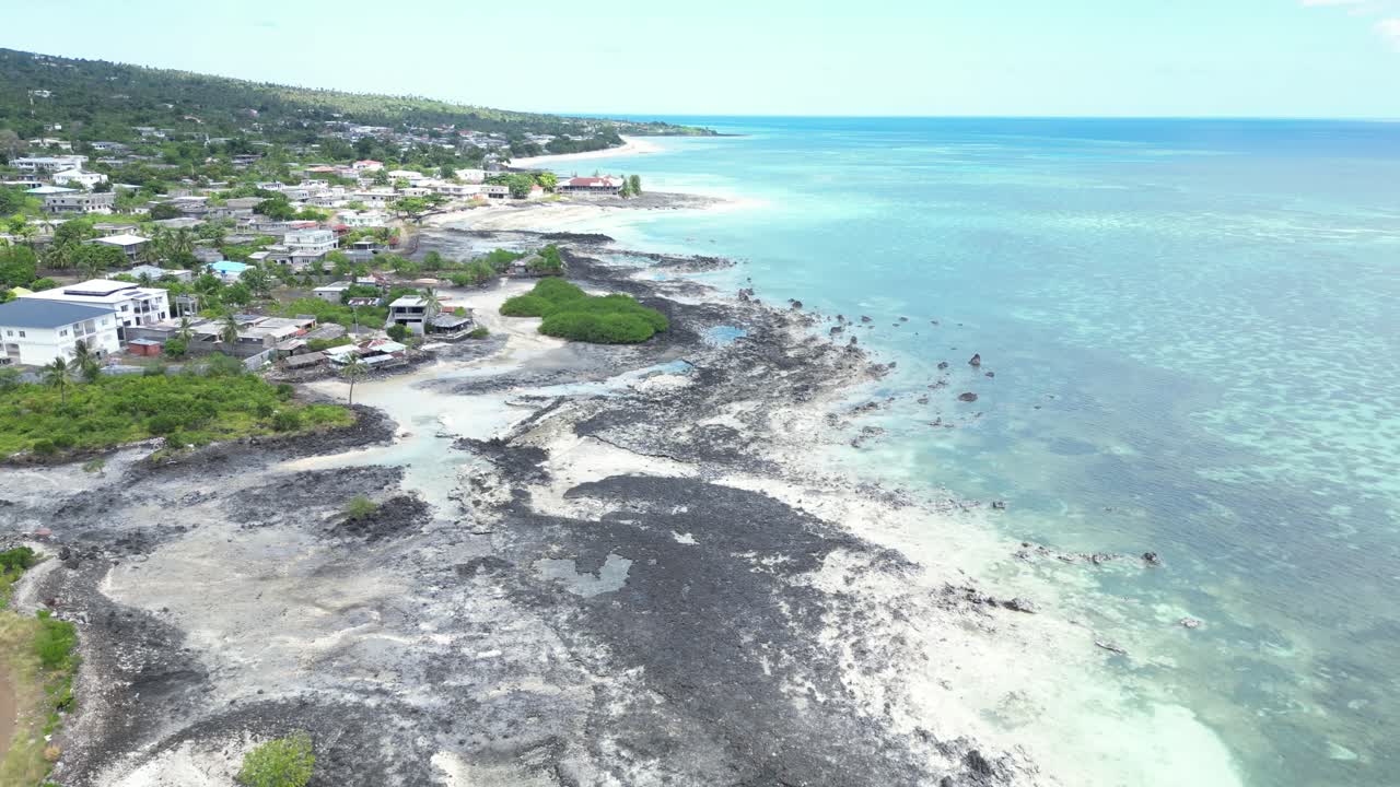 Aerial view of coastal town with volcanic rock formations and clear shallow waters