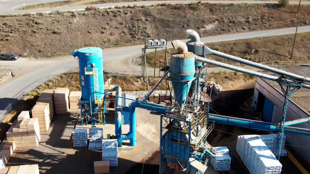 stellar pan zoom drone shot di un impianto di lavorazione di una segheria blu con automobili e fasci di tavole sullo sfondo in un ambiente desertico