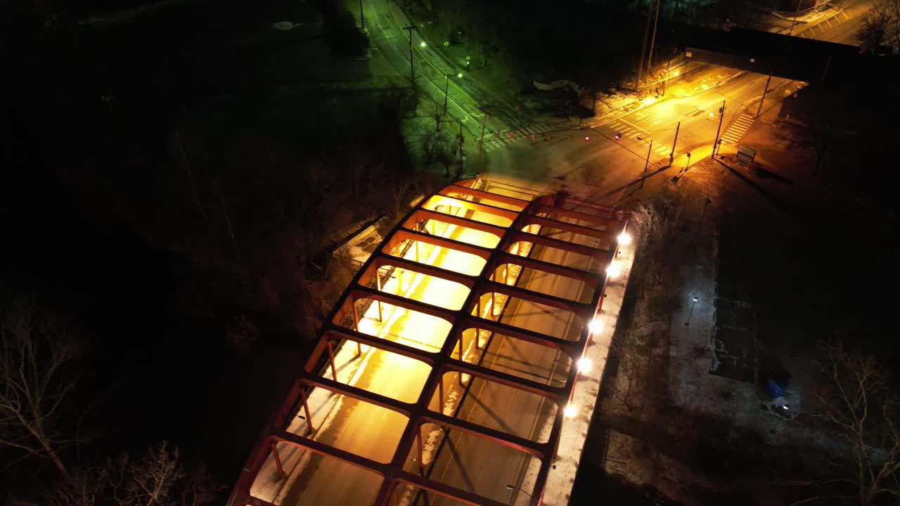 Spinning drone timelapse above a glowing pedestrian bridge in Youngstown, Ohio at night. Amber lights and urban streets create a mesmerizing circular motion.
