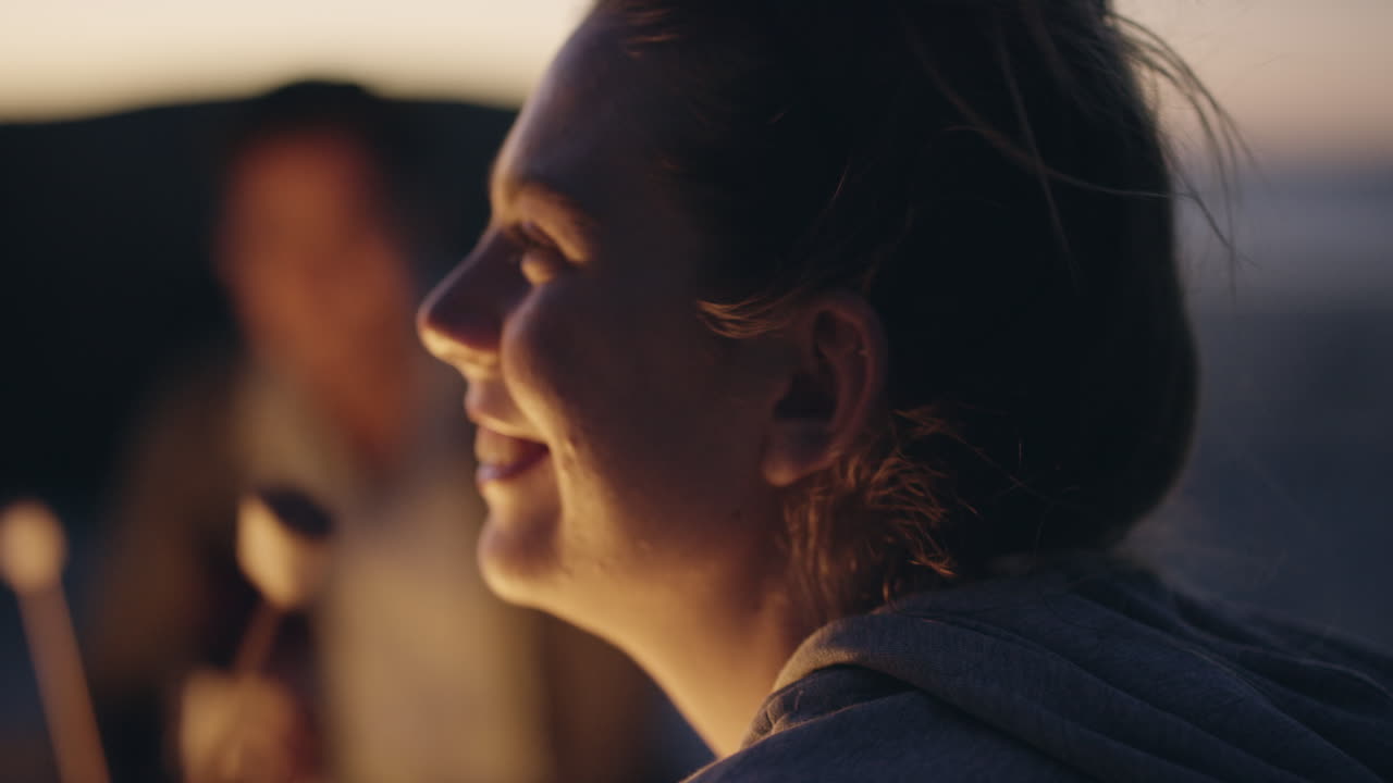 fiesta en la playa al atardecer con hoguera y malvaviscos asados con amigos