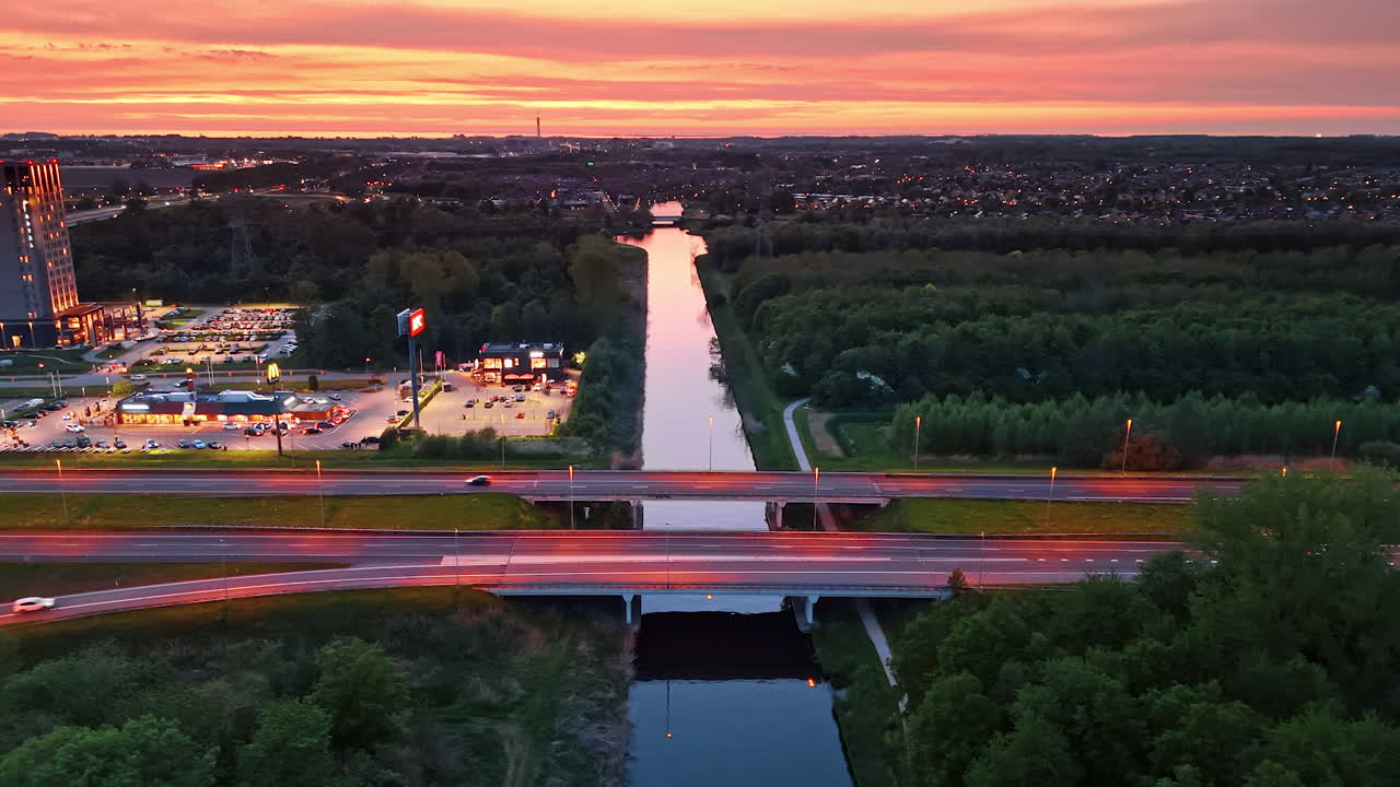 Canal sunset in the Netherlands. Vibrant sunset lights up the sky above a canal and highway, showcasing the beauty of the Netherlands at dusk
