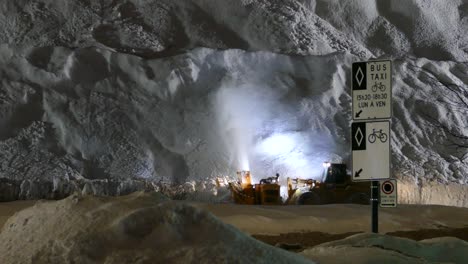 heavy snowplow working at night removing snow from the road on huge pile