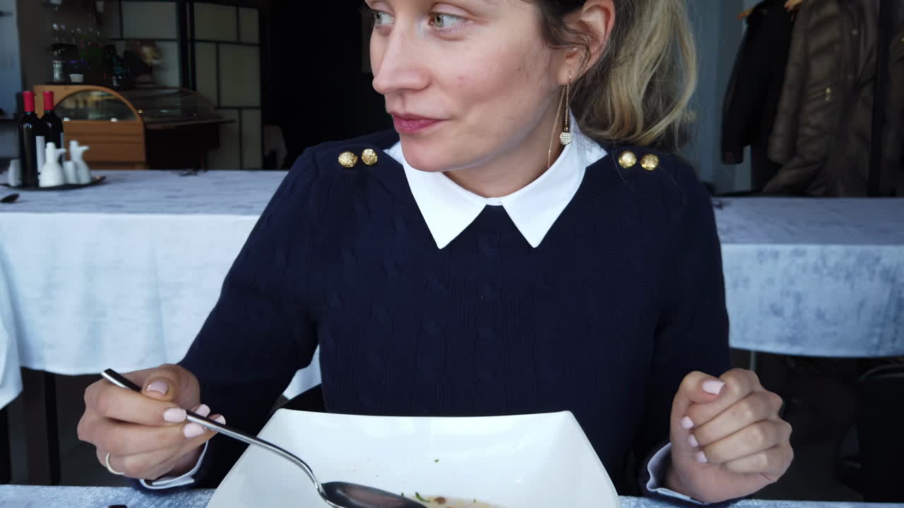 Close up of a woman eating chicken soup and smiling at a restaurant