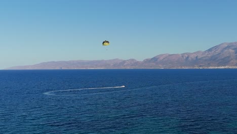 aerial parasailing adventure over the blue sea with distant mountains in crete greece