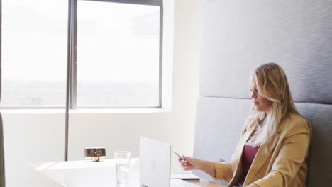 Plus-size-caucasian-casual-businesswoman-using-laptop-at-office-lounge