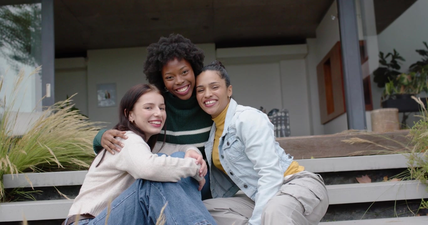 Diverse women friends left gesturing chatting center speaking, moving closer on porch steps, posing